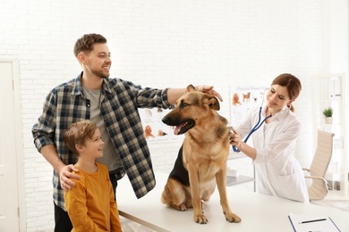 Photo of Father and son with their dog visiting veterinarian in clinic
