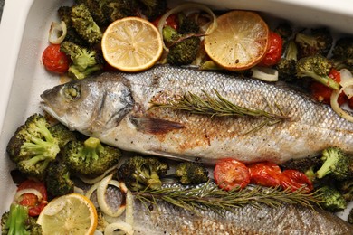 Delicious fish with vegetables in baking dish, flat lay