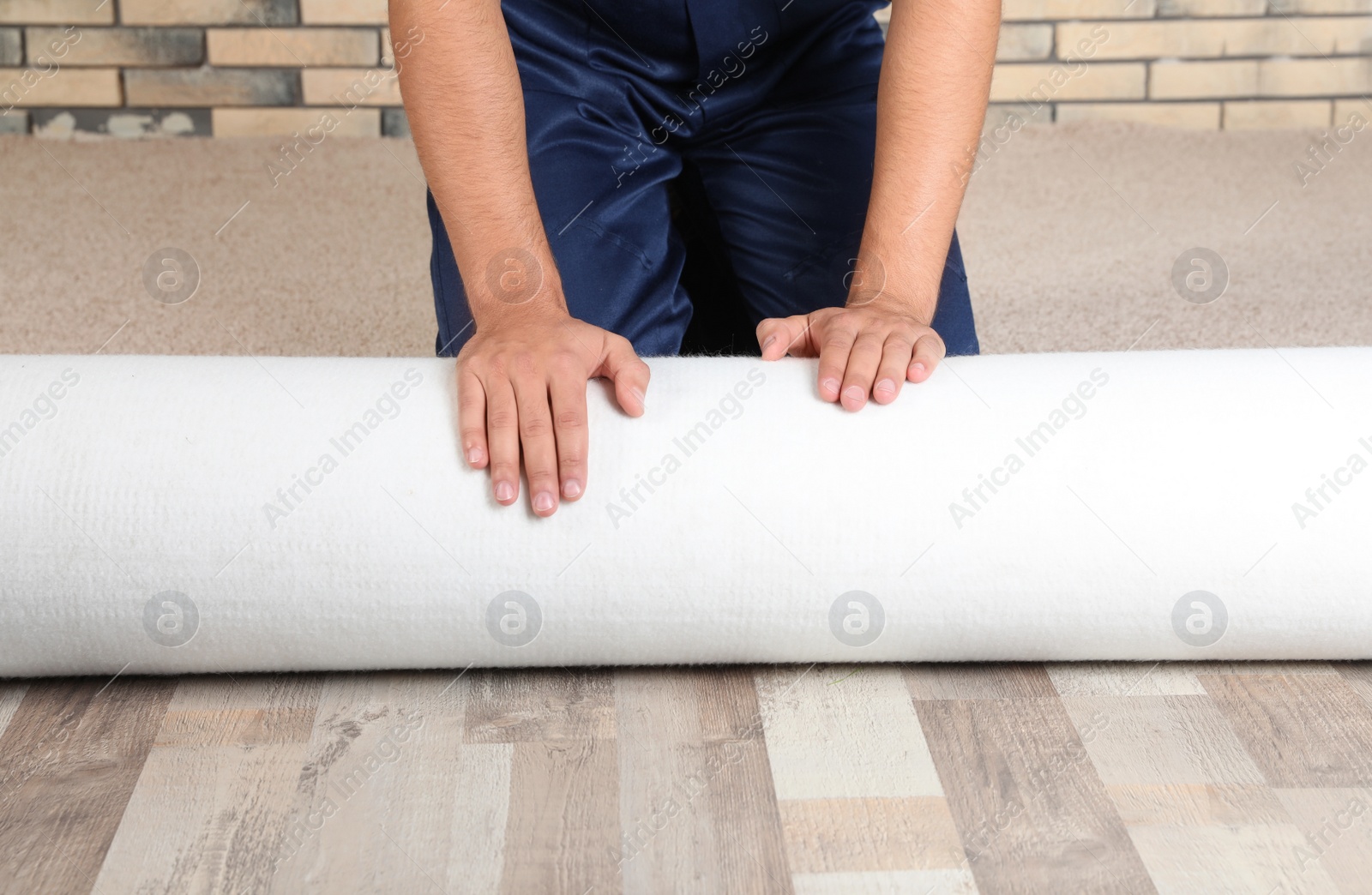 Photo of Man rolling out new carpet flooring indoors, closeup