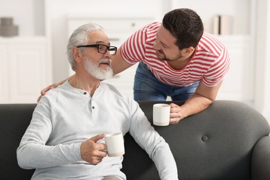 Photo of Happy son and his dad with cups at home