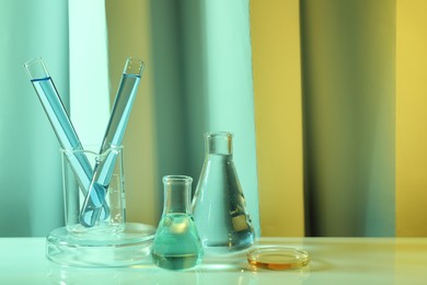 Laboratory analysis. Different glassware on table against color background, space for text
