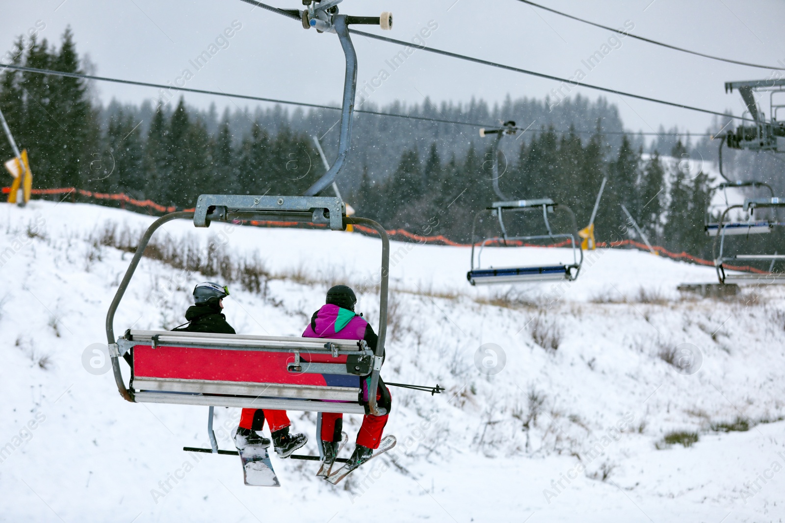 Photo of Chairlift with people at ski resort. Winter vacation