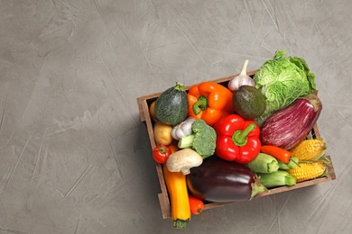 Photo of Crate with different fresh vegetables on grey background, top view. Space for text