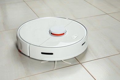 Photo of Robotic vacuum cleaner on white tiled floor