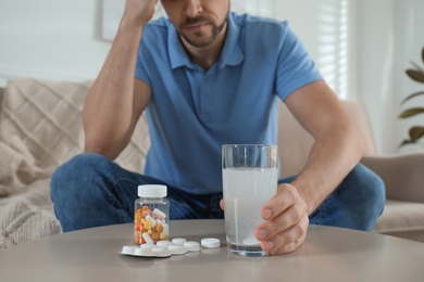 Photo of Man taking medicine for hangover at home, closeup
