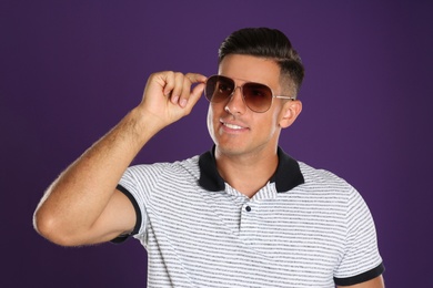 Photo of Handsome man wearing sunglasses on purple background