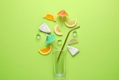 Photo of Flat lay composition with glass, ice, sliced fruits and coconut on color background. Summer cocktail recipe