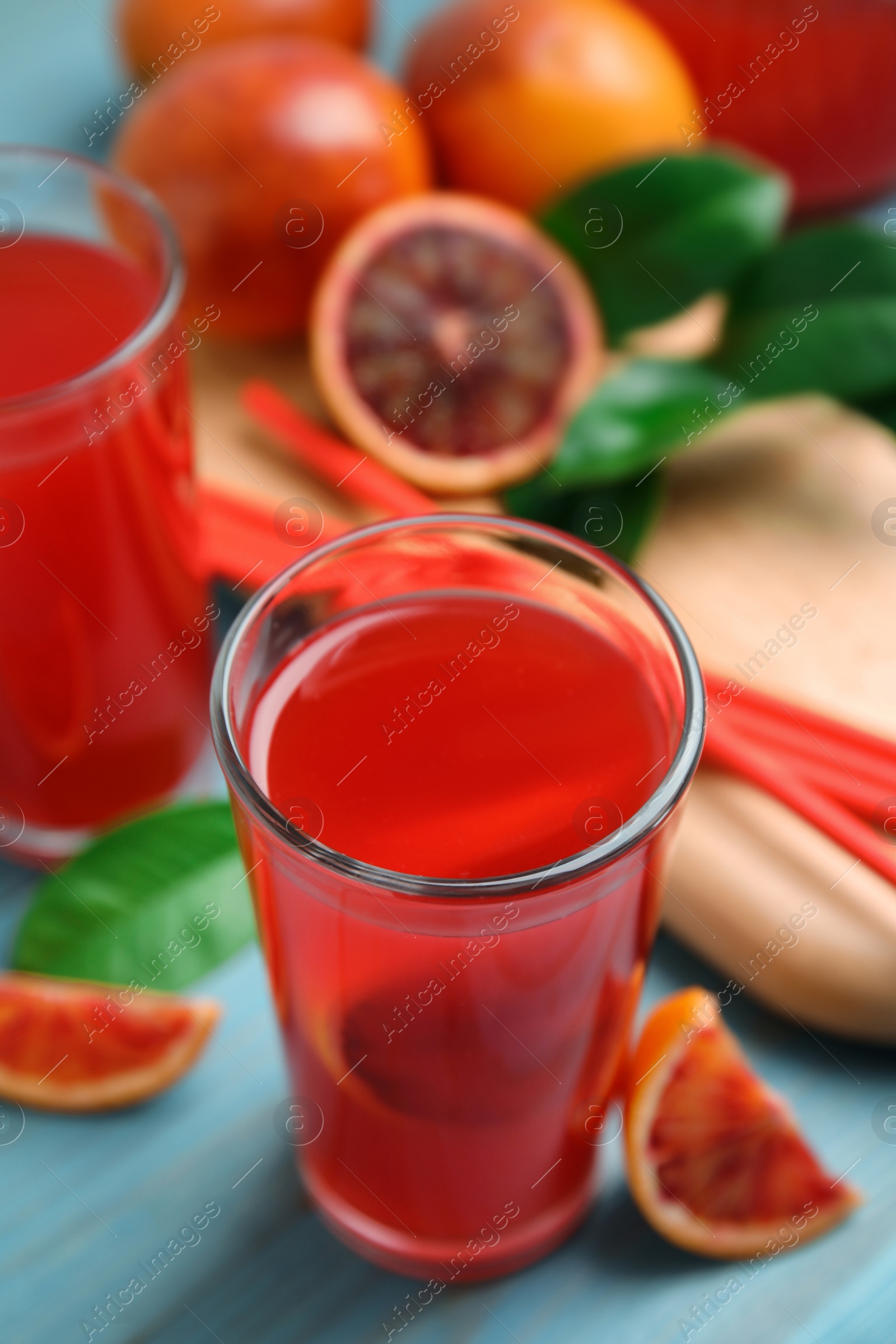 Photo of Tasty sicilian orange juice and fruits on light blue wooden table