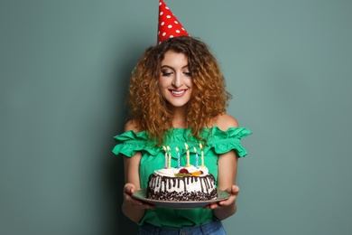 Photo of Young woman with birthday cake on color background