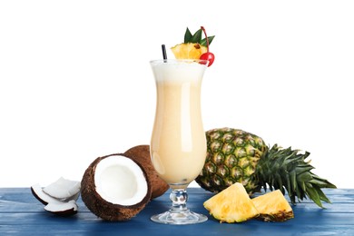 Tasty Pina Colada cocktail and ingredients on blue wooden table against white background