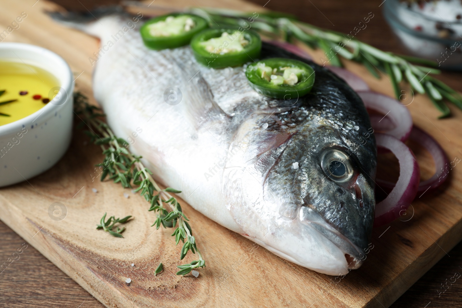 Photo of Fresh dorado fish and ingredients on wooden board, closeup