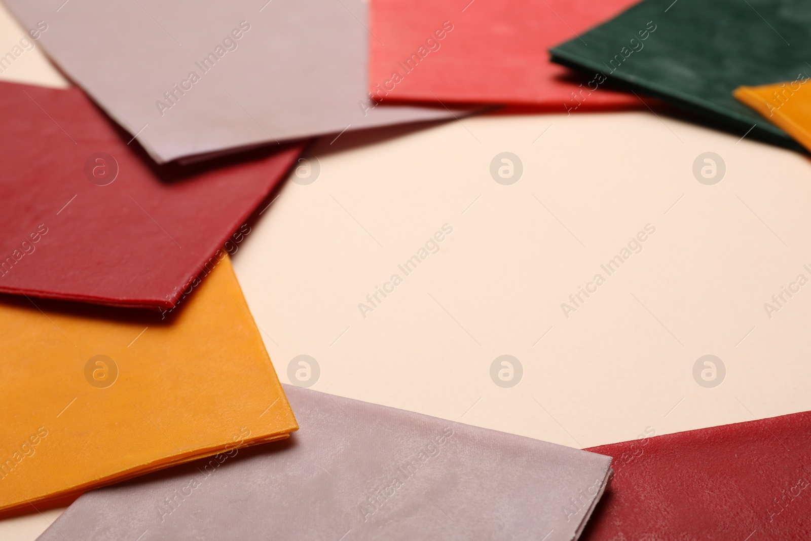 Photo of Frame of colorful reusable beeswax food wraps on beige background, closeup. Space for text