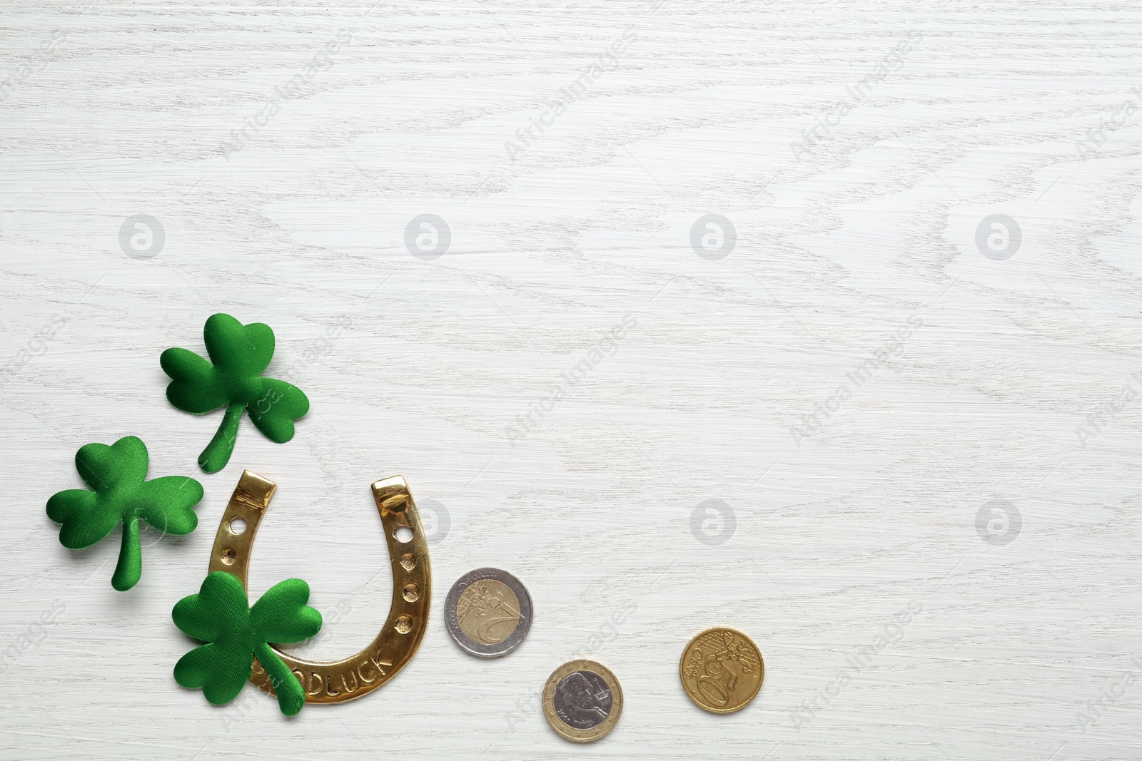 Photo of Golden horseshoe, decorative clover leaves and coins on white wooden table, flat lay with space for text. Saint Patrick's Day celebration