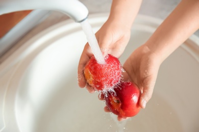 Woman washing fresh nectarines in kitchen sink, above view