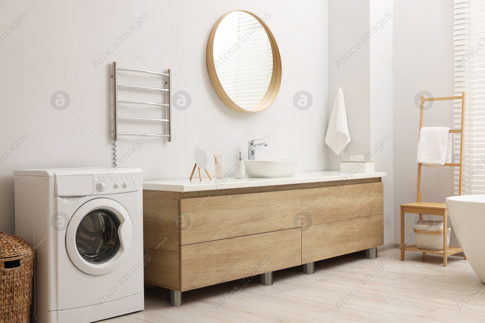 Photo of Stylish bathroom interior with heated towel rail and washing machine