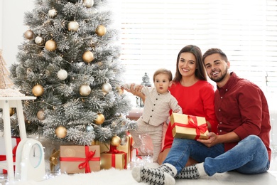 Photo of Happy family with cute baby near Christmas tree at home