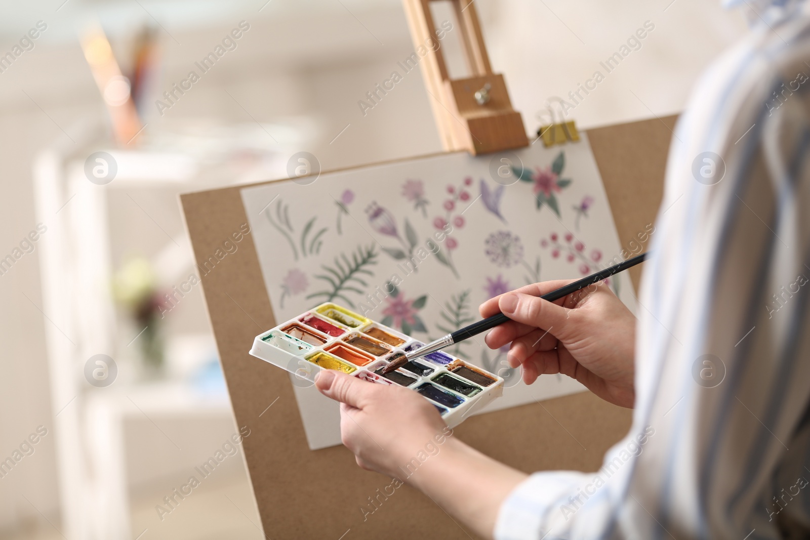 Photo of Woman painting flowers with watercolors in workshop, closeup