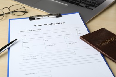 Photo of Visa application form for immigration, passport and pen on table, closeup