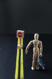 Photo of Development through barriers overcoming. Road Stop sign blocking way for wooden human figure with toy bicycle