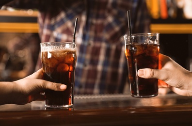 Photo of Couple with glasses of refreshing cola at bar counter, closeup
