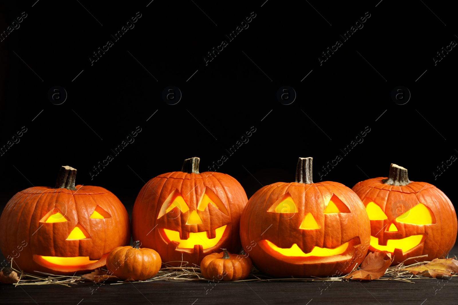 Photo of Pumpkin jack o'lanterns on table in darkness, space for text. Halloween decor