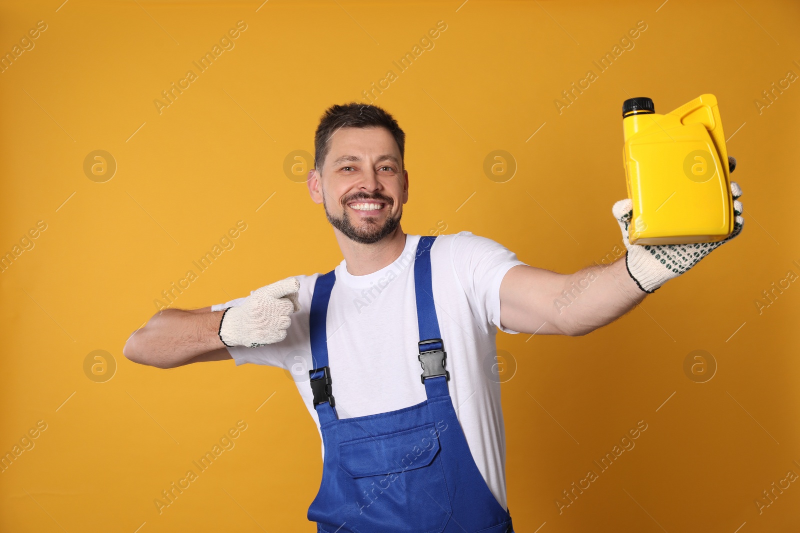 Photo of Man pointing at yellow container of motor oil on orange background