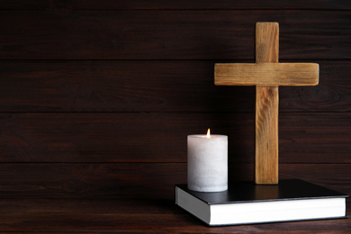 Photo of Cross, Bible and burning candle on wooden background, space for text. Christian religion