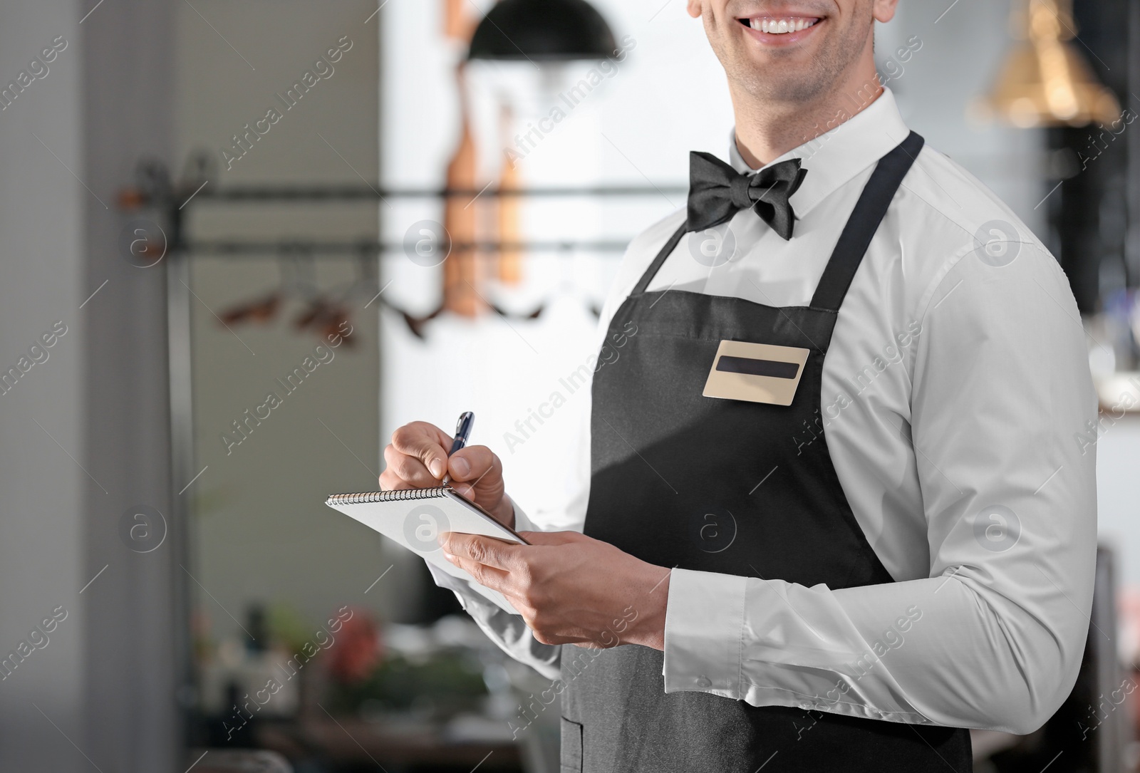 Photo of Waiter in elegant uniform with notebook at workplace