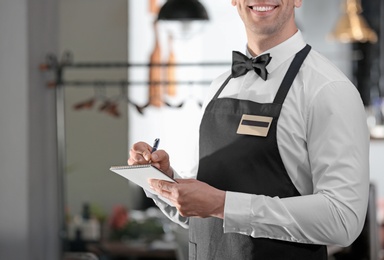 Photo of Waiter in elegant uniform with notebook at workplace