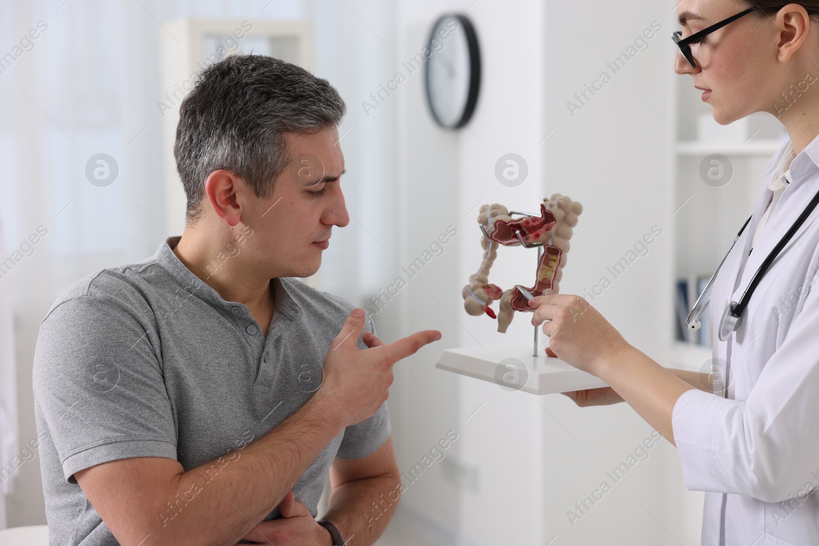 Photo of Gastroenterologist with anatomical model of large intestine consulting patient in clinic