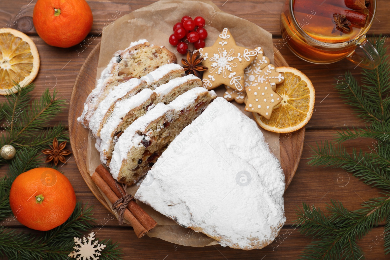 Photo of Traditional Christmas Stollen with icing sugar on wooden table, flat lay