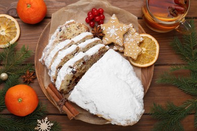 Traditional Christmas Stollen with icing sugar on wooden table, flat lay