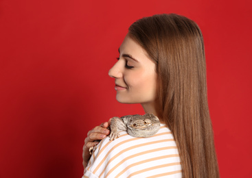 Photo of Woman holding bearded lizard on red background. Exotic pet