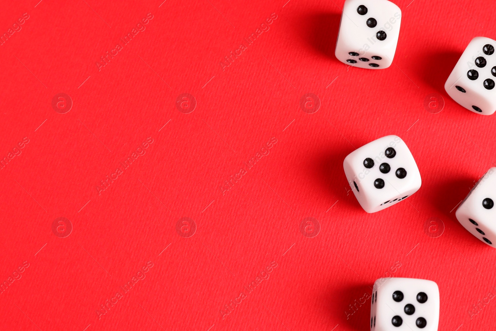 Photo of Many white game dices on red background, flat lay. Space for text