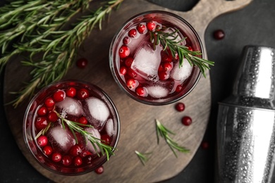 Photo of Tasty refreshing cranberry cocktail with rosemary and fresh ingredients on black table, flat lay