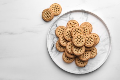 Photo of Tasty sandwich cookies with cream on white marble table, flat lay. Space for text