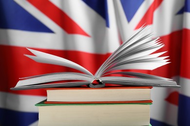 Photo of Learning foreign language. Different books against flag of United Kingdom