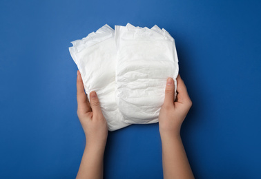 Photo of Woman with diapers on blue background, closeup