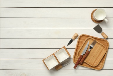 Set of modern cooking utensils on white wooden table, flat lay. Space for text