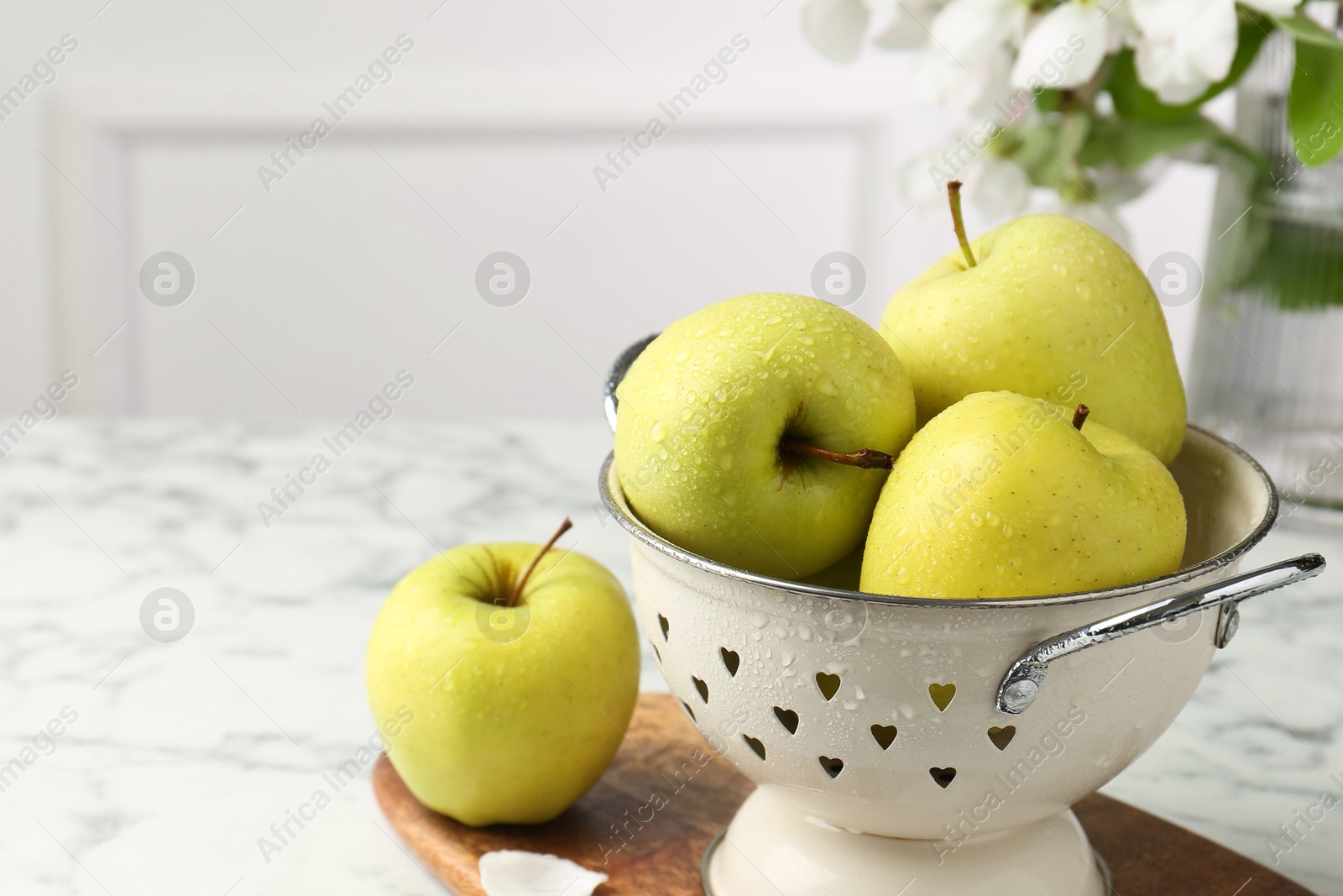 Photo of Colander with fresh apples on white marble table, space for text