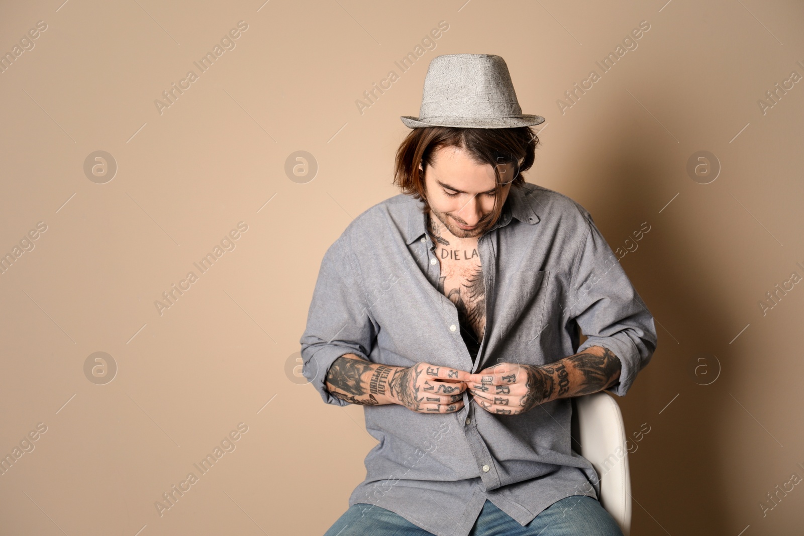 Photo of Young man with tattoos on body against beige background