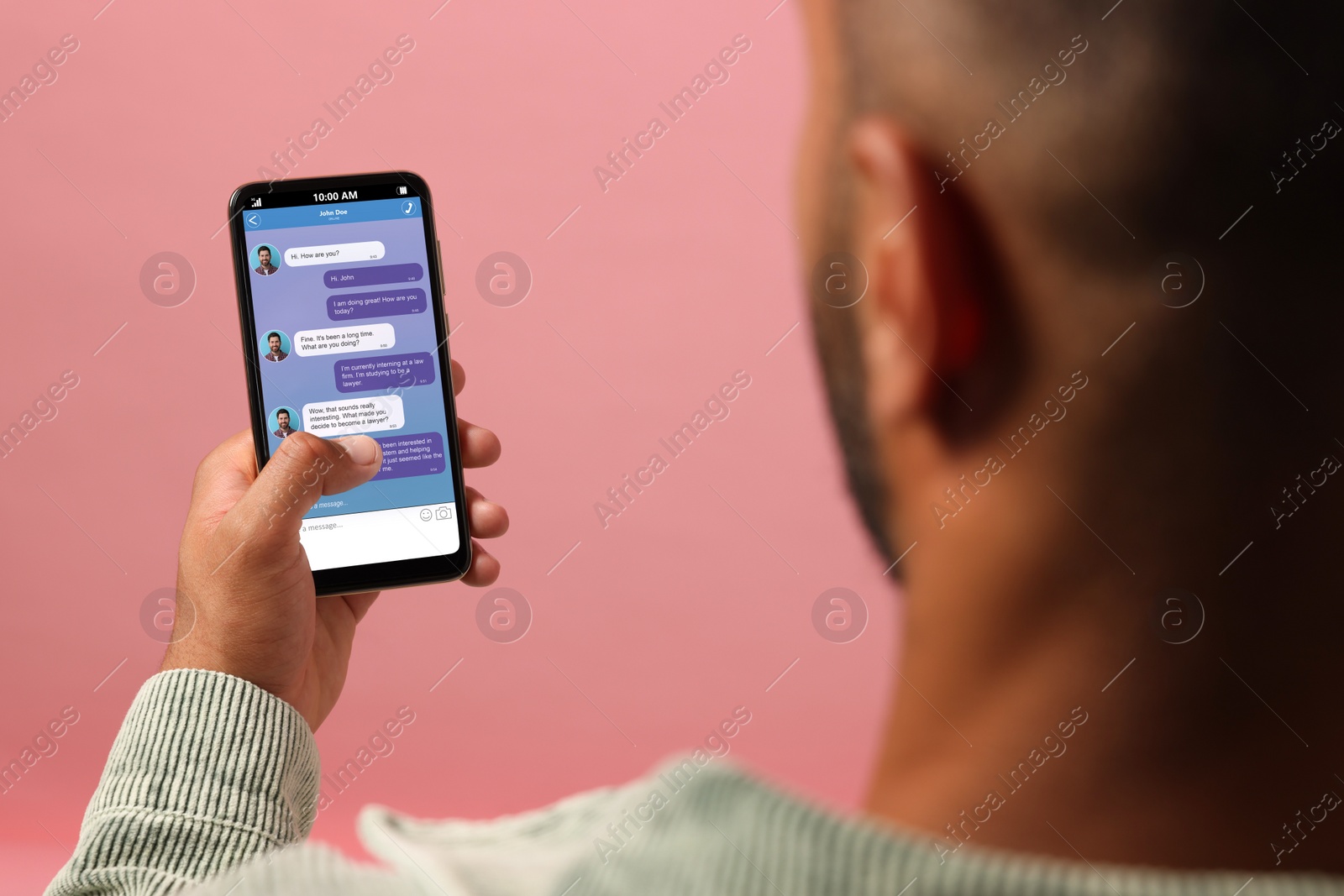 Image of Woman texting with friend using messaging application on smartphone against pink background, closeup