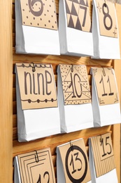 Photo of Paper bags with gifts on wooden wall, closeup. Christmas advent calendar