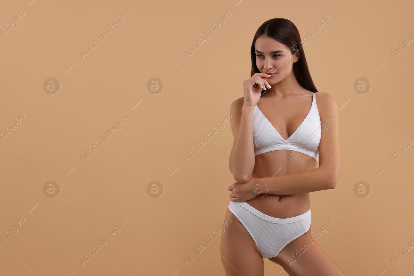 Photo of Young woman in stylish white bikini on beige background. Space for text