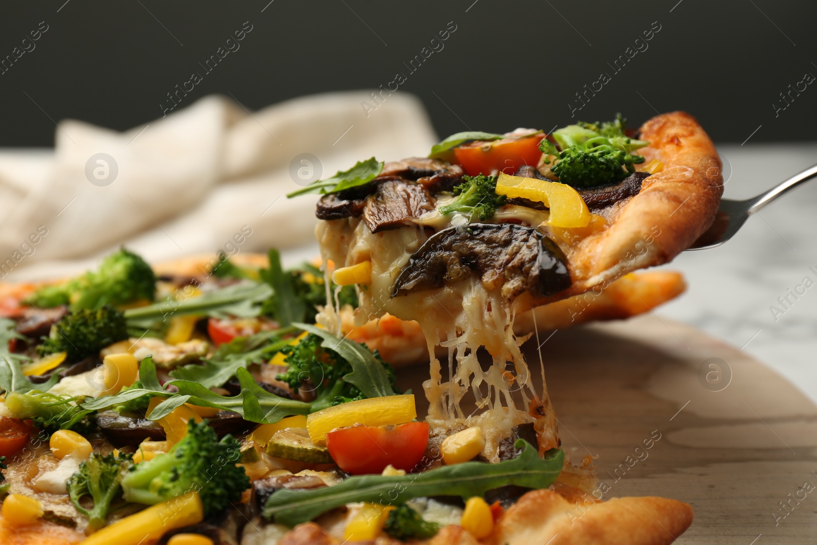 Photo of Taking piece of delicious vegetarian pizza at table, closeup