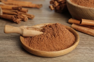 Aromatic cinnamon powder and scoop on wooden table