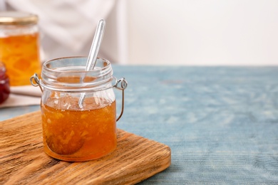 Photo of Jar with tasty sweet jam on wooden table