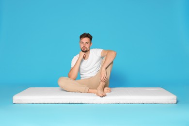 Photo of Man sitting on soft mattress against light blue background