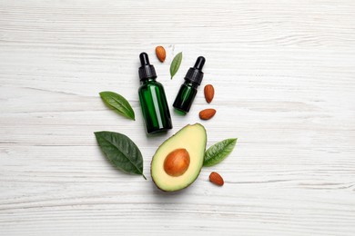 Flat lay composition with essential oil, almonds and avocado on white wooden table