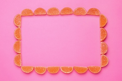 Photo of Frame made with orange marmalade candies on pink background, flat lay